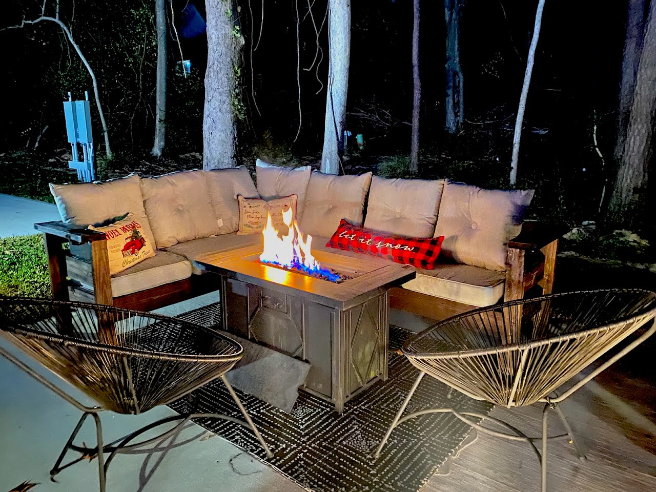 Outdoor lounge seating around a lit gas fire table at night