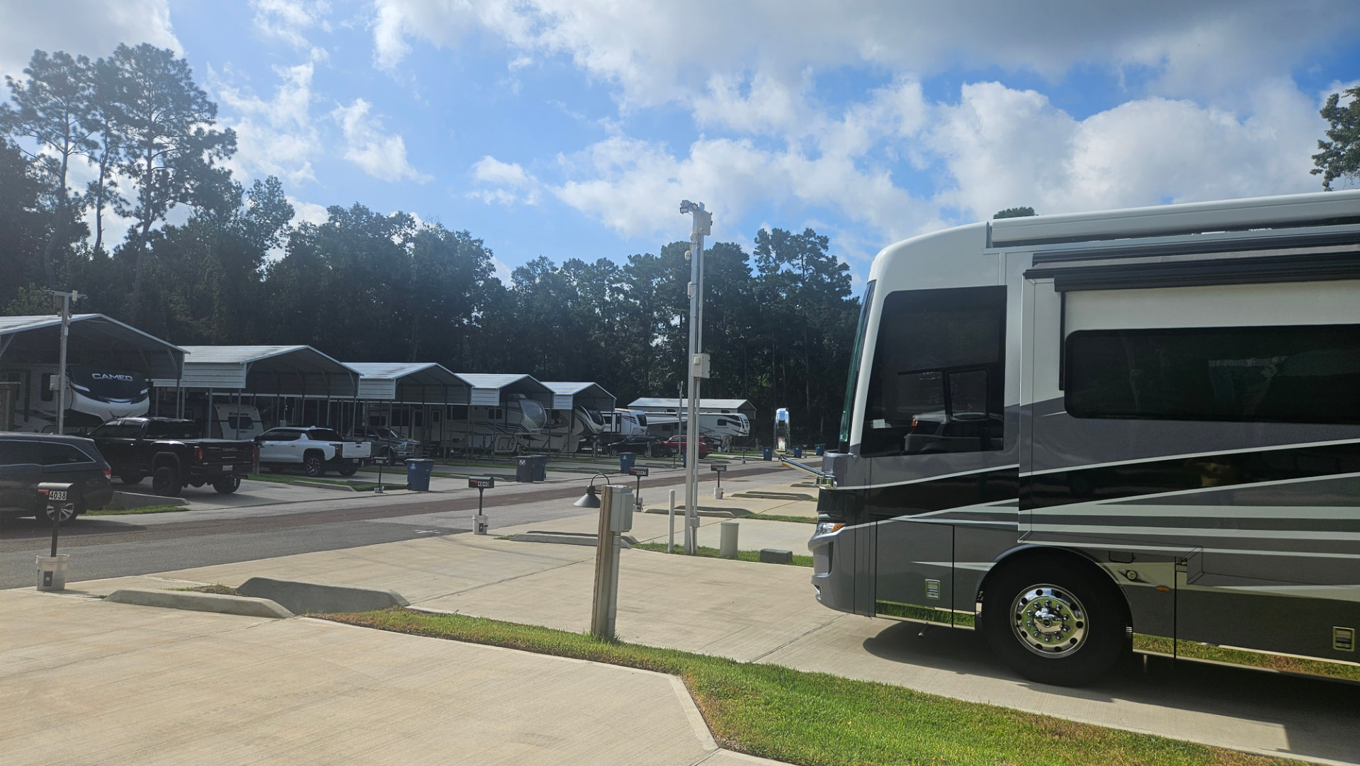 Motorhome parked on a concrete pad with covered spots in the background