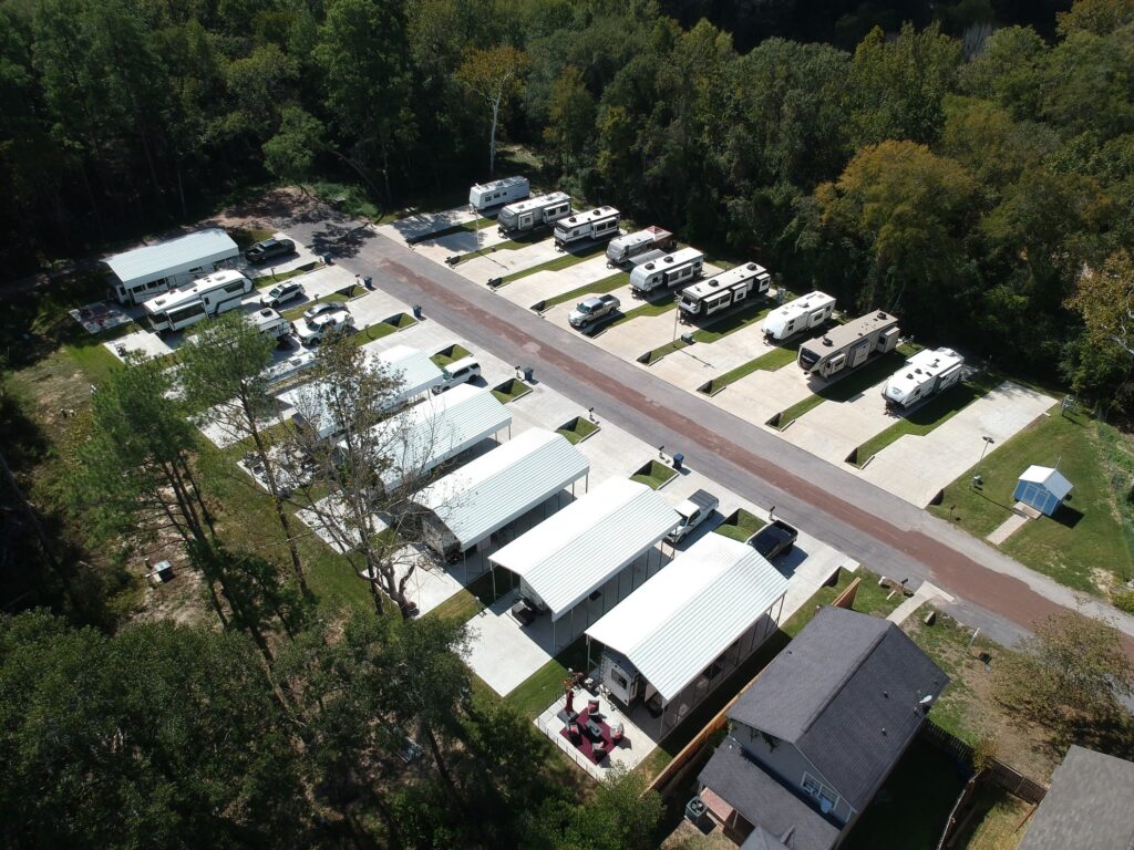 A travel trailer under tall pine trees at The Woodland RV Park
